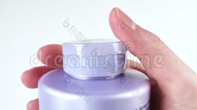 手指关闭紫色瓶子的盖子。 洗发水，护发素，沐浴露，沐浴泡沫，保湿护肤乳液。 自然